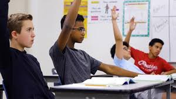 Middle school students raising their hands in the classroom